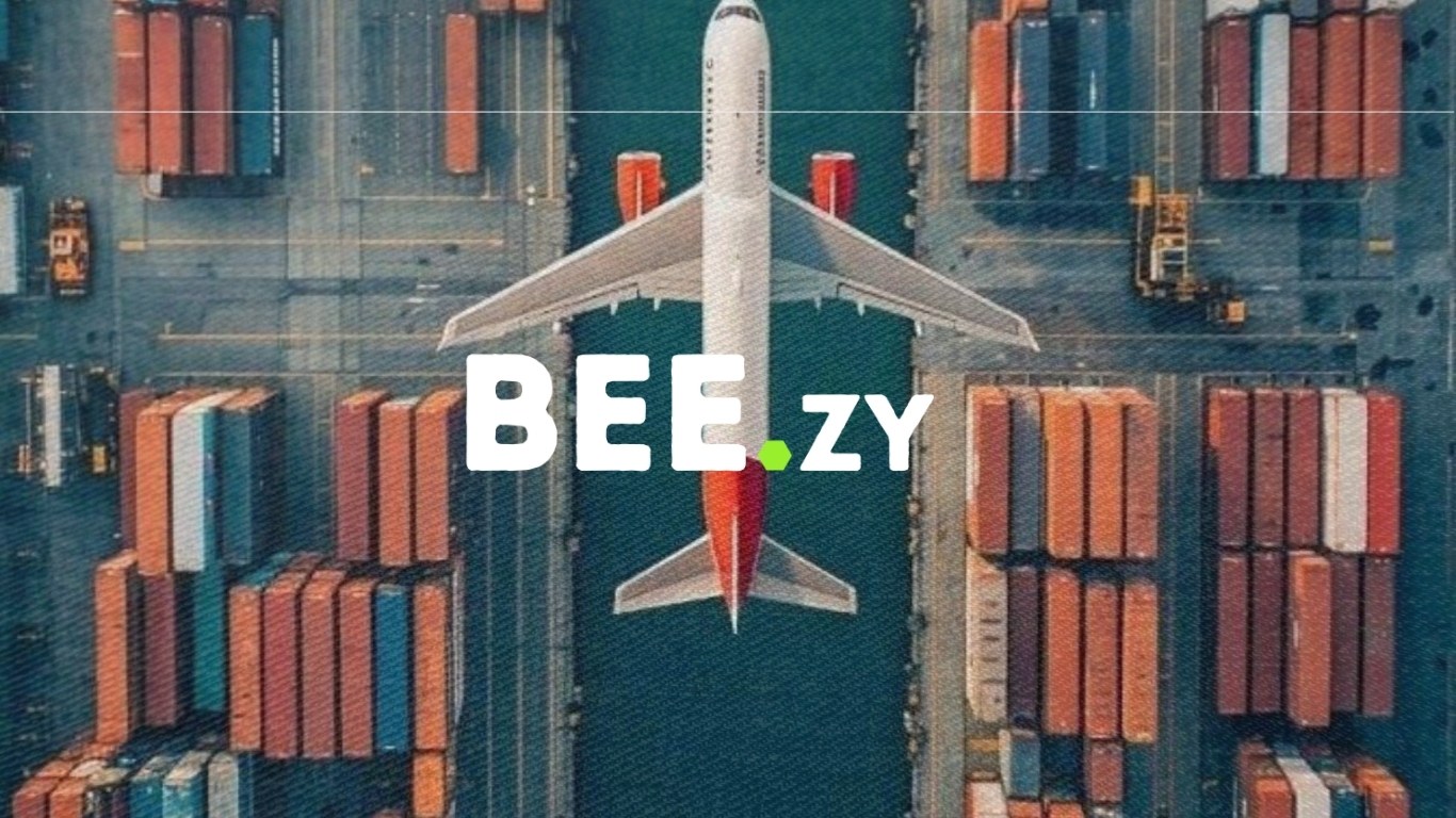 Aerial view of a cargo aircraft over a container terminal, with the BEE.zy logo